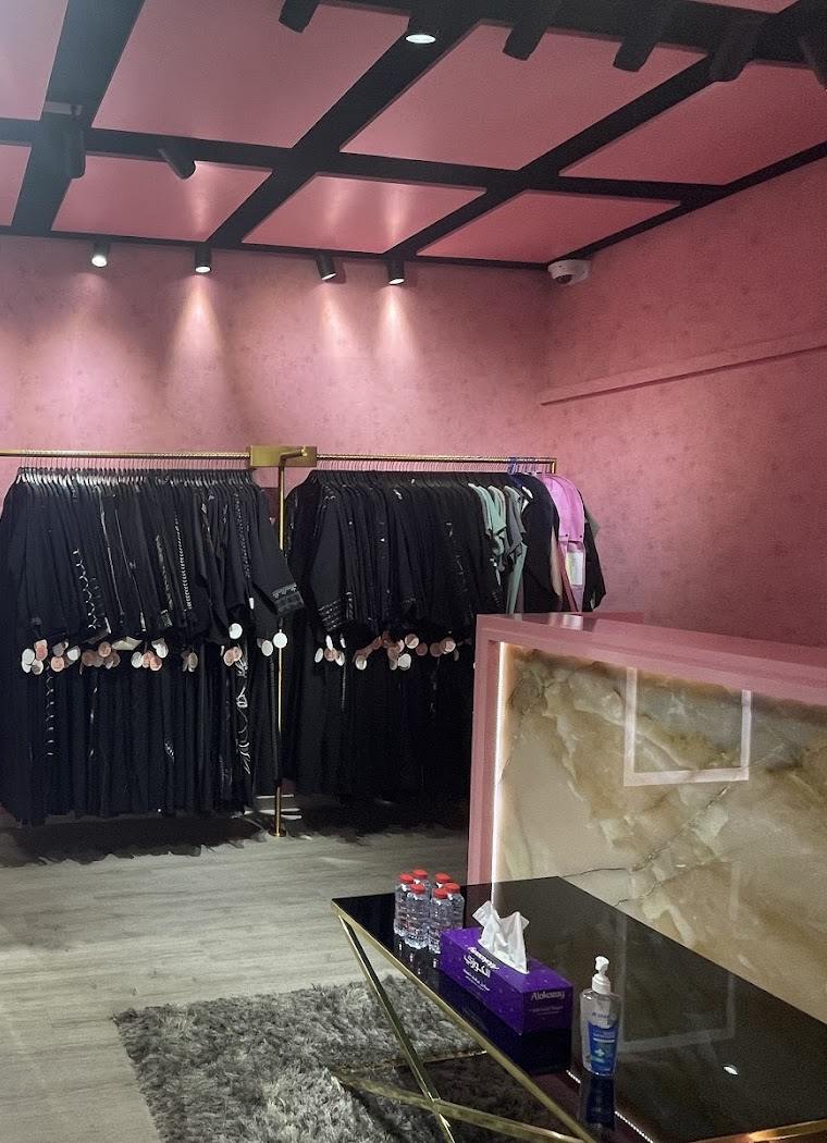 Black abayas with beaded sleeves on the rails, beside the onyx counter
