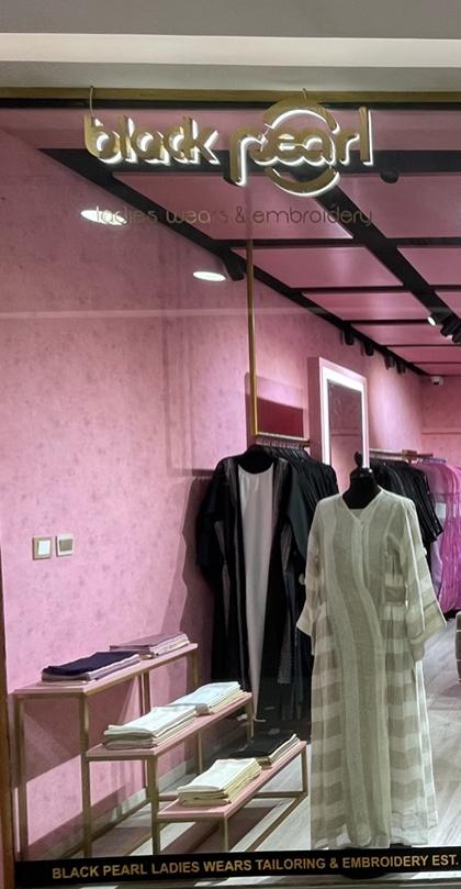 Window display: a black abaya and an ivory abaya on headless mannequins